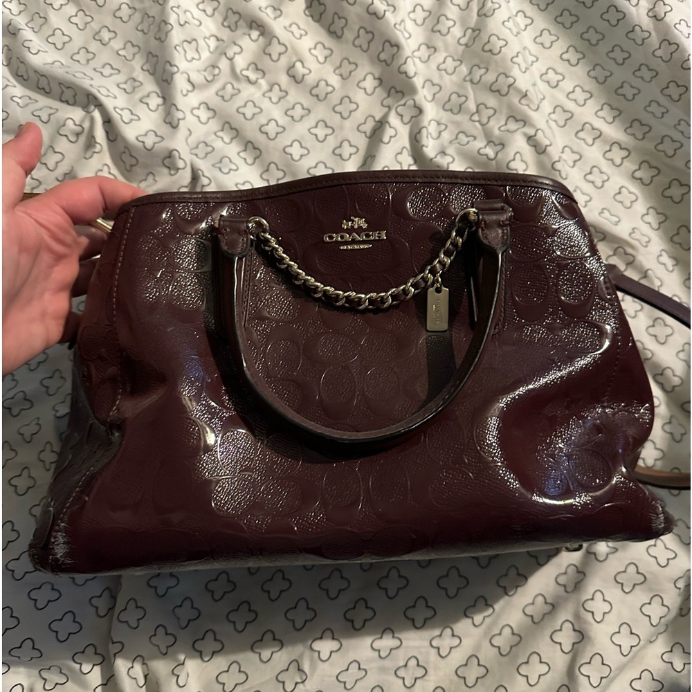 Medium, burgundy coach purse. Shoulder strap included.